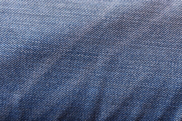 Texture of old crumpled faded blue jeans close-up.