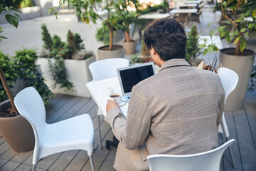 Young man using notebook in outdoor cafe