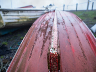Keel ship of an old fishing boat in focus. Red hull. Background out of focus and in a mist.