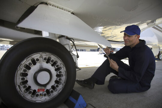 Mechanic examining tire of private jet