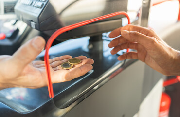 Selective focus on the hand of a bus driver taking the money from a customer's ticket.