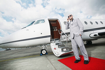 Man with headset standing by private jet
