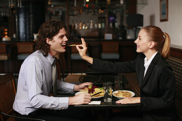 Businesswoman feeding businessman crisp