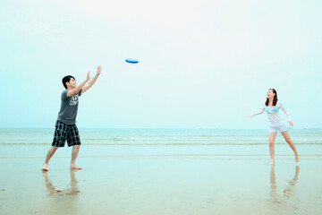 Man and woman playing with flying disc on the beach