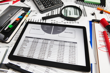 Top view of office employee's desk - work with tablet pc computer and financial reports, analysis and accounting, tables and graphs, various office items for bookkeeping