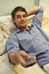 Obraz premium Man lying on bed holding remote control