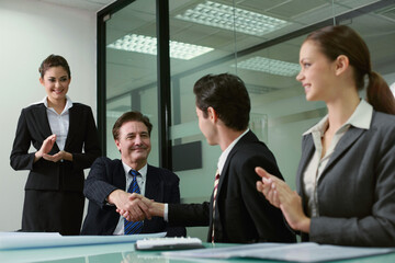 Businessmen shaking hands, businesswomen applauding