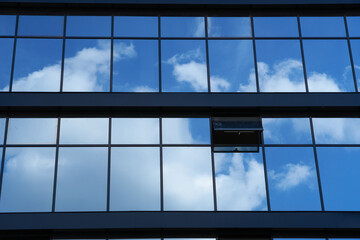 Fototapeta na wymiar facade of a modern building on a bright Sunny day, blue sky and clouds reflecting in a glass, beautiful exterior of the new building