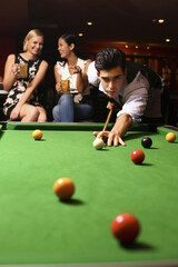 Man playing pool, women watching