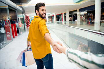 Come with me. Photo of cheerful handsome guy leading girlfriend to secret surprise place carry many...