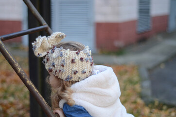 Picture of a smiling blonde toddler girl playing outside in the funny knitted headband