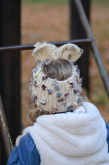 Picture of a smiling blonde toddler girl playing outside in the funny knitted headband