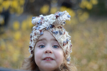 Picture of a smiling blonde toddler girl playing outside in the funny knitted headband