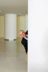 Businessman smiling from behind a pillar