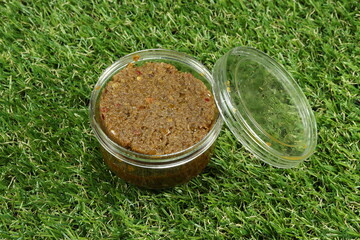Traditional tamarind paste with pickled shrimp and local herbal vegetable in the plastic packaging on the green grass. Famous souvenir from floating market in Thailand. 