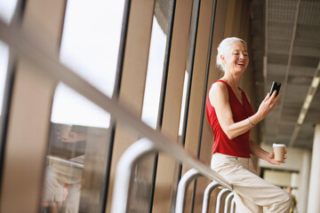 Businesswoman holding a cup of coffee while reading text message in phone