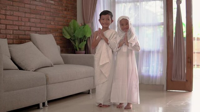 two children greeting wearing muslim white ihram at home. umrah concept