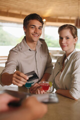 Man and woman drinking at the bar, man paying for the drinks