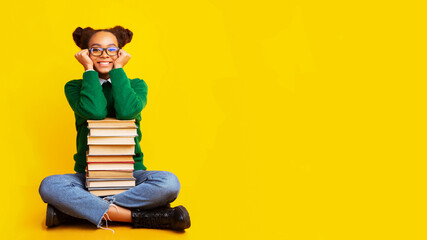 Afro schoolgirl with stack of books at studio
