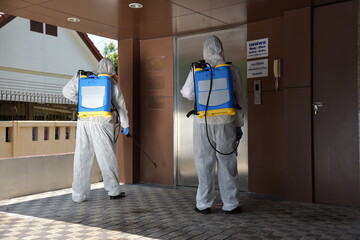 Two Asian men in protective germ suit or PPE suit with Equipment Face shield, Mask, and Alcohol gel for cleaning place and  spreading for fighting Corona virus/Outbreak quarantine/disinfection