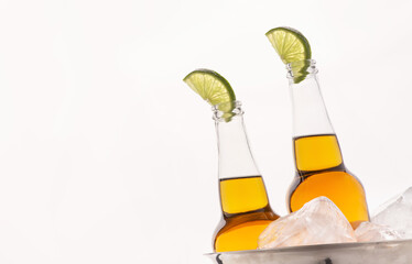 Cold drink. Transparent beer bottles with light ale and slice of lime in metal bucket with ice
