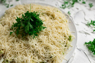 Layered salad with grated hard cheese with lettuce leaves and watercress greens on a white concrete background with texture