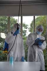 Two Asian men in protective germ suit or PPE suit with Equipment Face shield, Mask, and Alcohol gel for cleaning place and  spreading for fighting Corona virus/Outbreak quarantine/disinfection