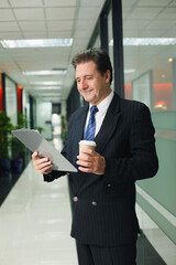 Fototapeta premium Businessman holding clipboard and a cup of coffee