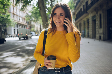 Young positive woman smiling while talking on smartphone device, attractive hispanic student girl...
