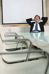 Businessman sitting with hands behind head