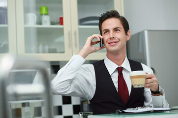 Businessman talking on the phone while drinking coffee