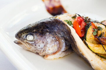 Baked trout on a plate. Delicious fish meal filled with vegetable ragout and served with potato puree. Studio shot.