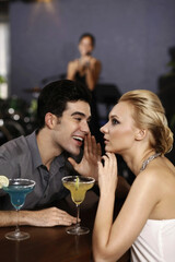 Man whispering into woman's ear