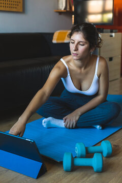 Young woman using tablet for following fitness workout online class at home.