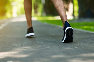 Unrecognizable jogger in sports shoes running at park in morning, close up