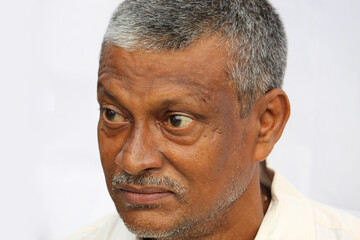 Obraz premium Angry senior Indian man face portrait on white background. Old man looking side way.