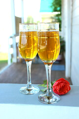 On the summer terrace, two glasses of drink, a rose. Rest and romance.