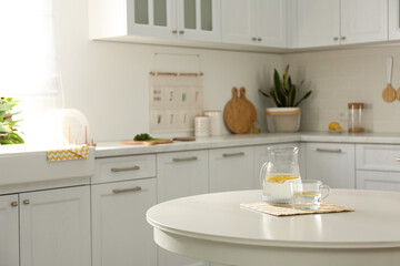 Fresh lemonade on white round table in kitchen. Stylish interior design