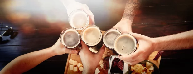 Foto op Plexiglas Kroeg Groep vrienden roosteren met bier in pub, bovenaanzicht. Bannerontwerp