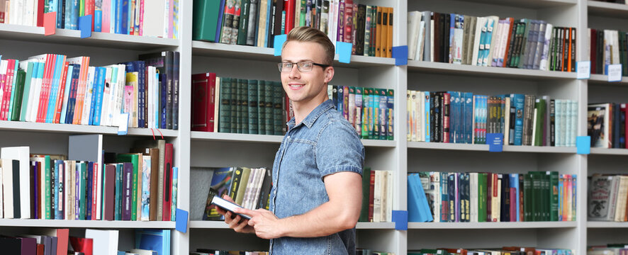 Student with book near shelving unit in library. Banner design