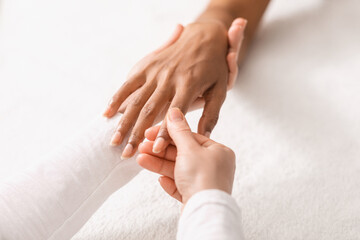 Top view of therapist rubbing black woman fingers