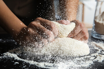 Fototapeta premium Young woman kneading dough at table, closeup