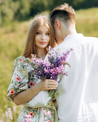 A gorgeous young couple in love hugging in a field of flowers