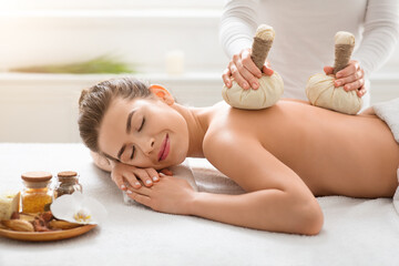 Obraz na płótnie Canvas Masseuse making body massage with herbal compress balls