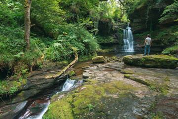 a man looks at one of the waterfalls of the Ajan river near the town of Vega de Pas in Cantabria