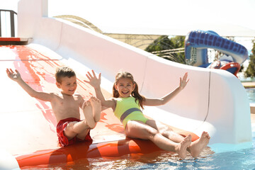 Happy children on slide at water park. Summer vacation