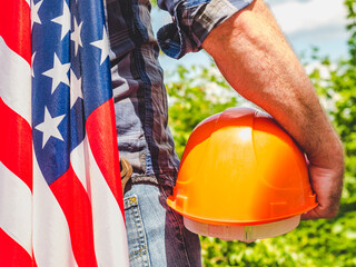 Handsome man with tools, holding an American Flag. View from the back, close-up. Concept of work...