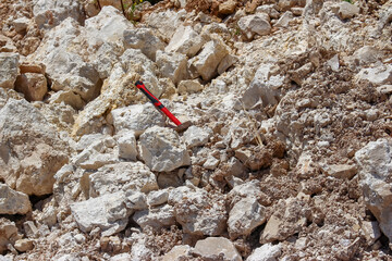 Limestone stones in a quarry and geological hammer, search for fossils