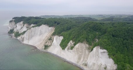 Møn Cliffs from the sky in a traditional Danish overcast day. Coastline visited by tourists for the chalk cliffs hanging over the turquoise Baltic sea.  - Powered by Adobe