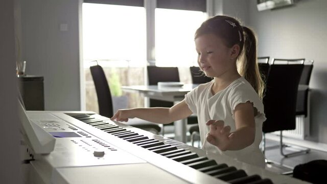 Little girl learns to play the piano. She really likes to press keys.